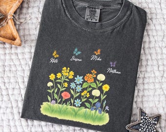 May include: A dark gray t-shirt with a floral design featuring butterflies and the names Kate, Susan, Mike, and Nathan.