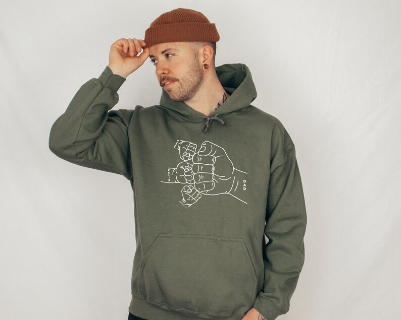 May include: A green hooded sweatshirt with a white graphic of several hands clasped together in a fist bump. The text "DAD" is printed on the right side of the graphic.