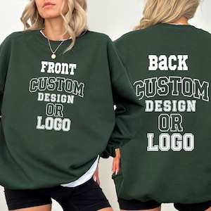 May include: A dark forest green crewneck sweatshirt featuring white collegiate-style lettering. The front displays the text FRONT CUSTOM DESIGN OR LOGO, while the back displays the text BACK CUSTOM DESIGN OR LOGO in a matching white font style.