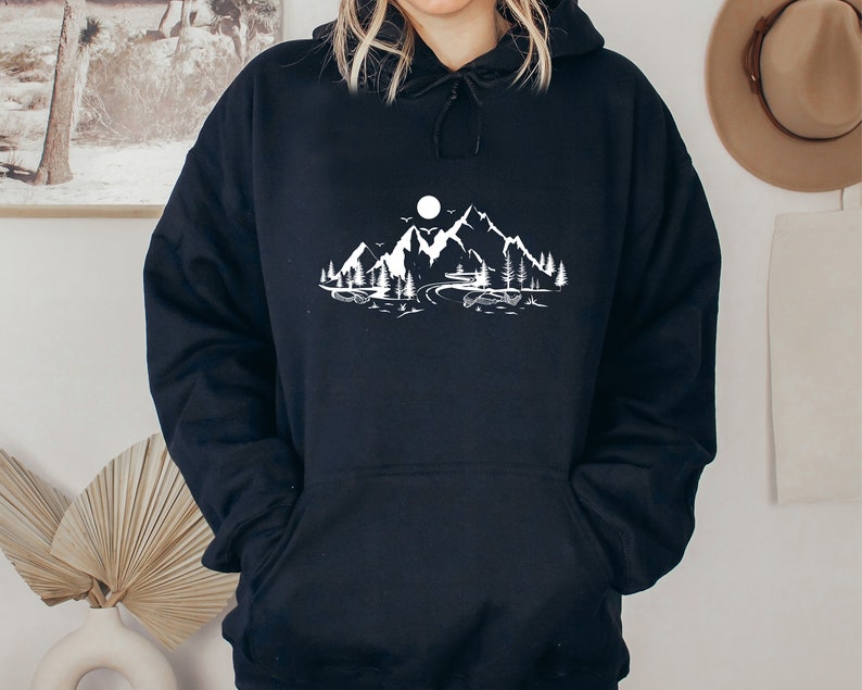 K&ouml;nnte beinhalten: Schwarzer Kapuzenpullover mit einem wei&szlig;en Motiv von Bergen, einem See und einem Mond.