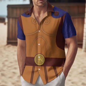 Peut inclure: Une chemise boutonnée à manches courtes de couleur marron et bleue avec un motif de personnage de dessin animé. La chemise présente une pièce de poitrine marron avec une boucle de ceinture dorée et un col bleu.