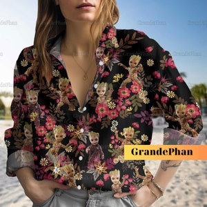May include: A black button-down shirt with a floral print featuring a cartoon character. The character is green and has a brown face. The shirt has long sleeves and a collar.