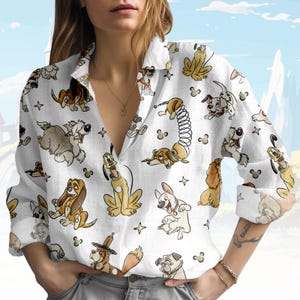 May include: White button-down shirt featuring a repeating pattern of cartoon dogs in various poses. The long-sleeved shirt has a classic collar and is made of a lightweight fabric. The dog illustrations include characters like Pluto and Lady.