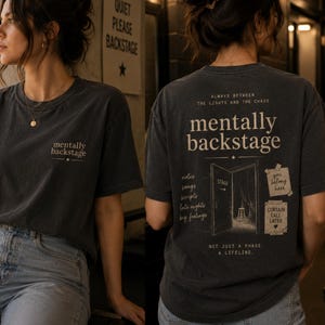 May include: Charcoal grey t-shirt with the words "mentally backstage" printed on the front and back. The back design includes a stage door graphic and the text "Always between the lights and the chaos" and other phrases.