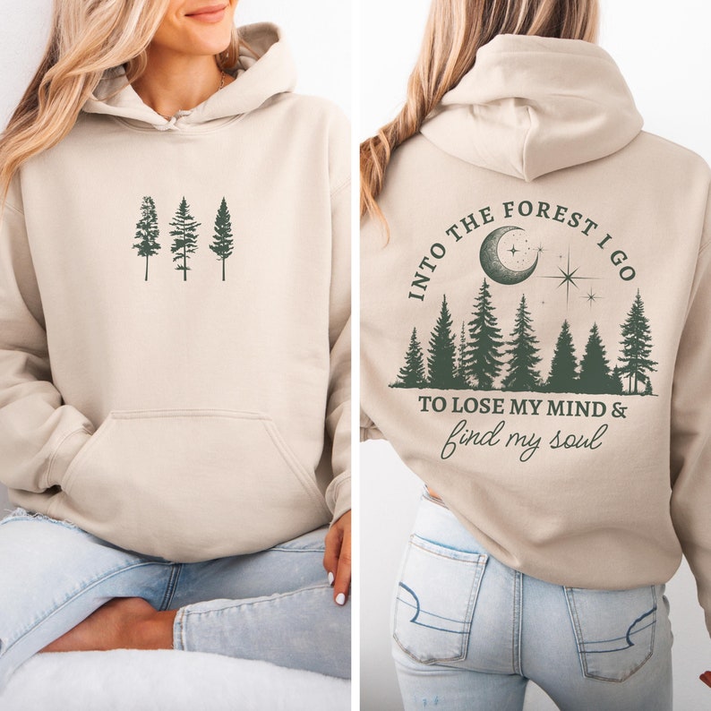 May include: A beige hooded sweatshirt with a forest scene on the back. The text on the back reads 'Into the forest I go to lose my mind & find my soul.' The front of the sweatshirt has a simple design of three trees.