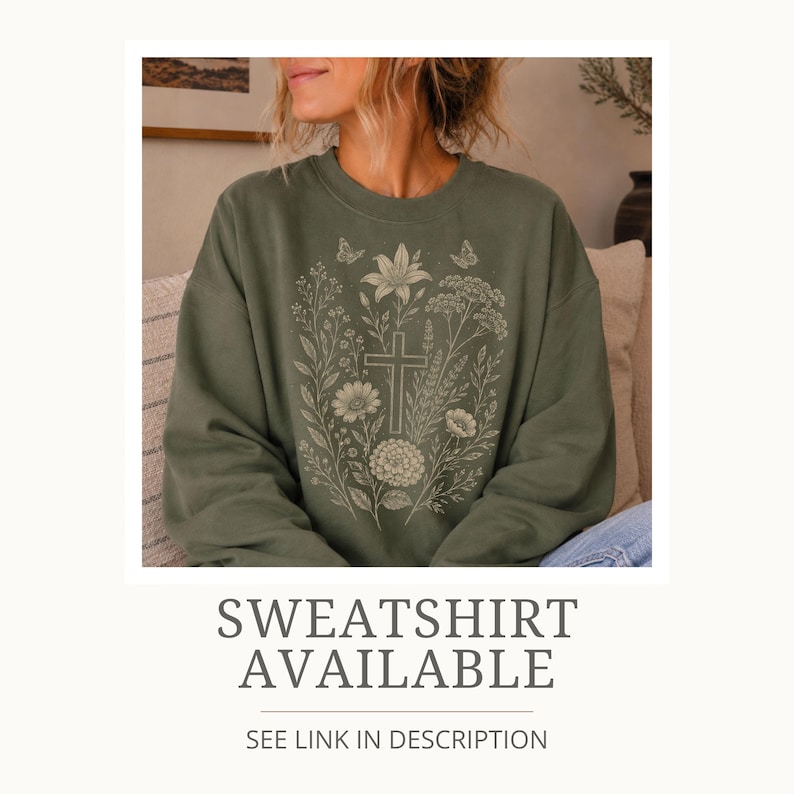 May include: An olive green crewneck sweatshirt featuring a light-colored line art graphic on the chest. The design depicts a central cross surrounded by various wildflowers, foliage, and two small butterflies in a botanical illustration style.