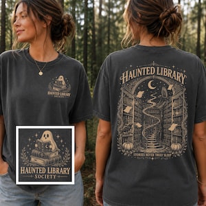 Op de afbeelding: Een antracietgrijs t-shirt met een kleine afbeelding op de voorkant van een geest die een boek leest met de tekst "HAUNTED LIBRARY SOCIETY". De achterkant toont een grote illustratie van een bibliotheek met een wenteltrap, een maansikkel en de tekst "HAUNTED LIBRARY STORIES NEVER TRULY SLEEP".