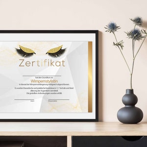 Op de afbeelding: Een wit certificaat met gouden accenten en een gouden glitterontwerp van twee wimpers. De tekst op het certificaat luidt "Zertifikat" en "Wimpernstylistin".