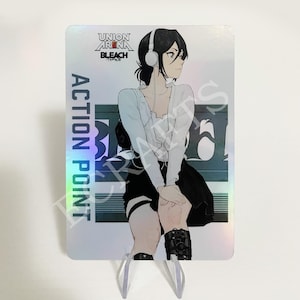 May include: A holographic trading card featuring a character from the anime Bleach. The character is a young woman with black hair and wearing a white shirt, black skirt, and black boots. She is wearing headphones and has a serious expression on her face. The card has the text "UNION ARENA BLEACH" and "ACTION POINT" on it.