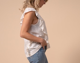 May include: A woman wearing a white eyelet top with ruffles and blue denim jeans. She is wearing leopard print shoes.