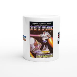 Könnte beinhalten: Weißer Keramikbecher mit Retro-Videospielgrafik. Das Design zeigt einen Astronauten, ein Raumschiff und den Spieletitel "JETPAC". Der Text lautet "For the 16 or 48K RAM Sinclair ZX Spectrum".