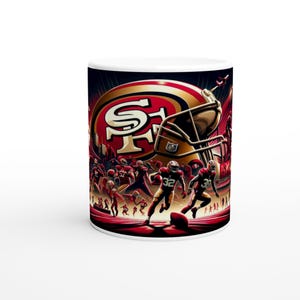 May include: White ceramic mug with a football design. The image shows a helmet, team logo, and players in action. The colour scheme is red, gold, and black, with a stadium background. The mug is suitable for hot beverages.