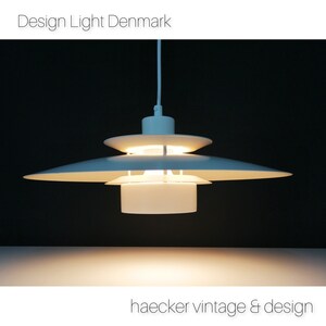 May include: White pendant light fixture with a circular, layered design. The light is on and illuminating the room.