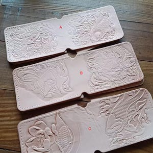 May include: Three leather wallets with different embossed designs. The first wallet has a koi fish design, the second wallet has a dragon design, and the third wallet has a lotus flower design.
