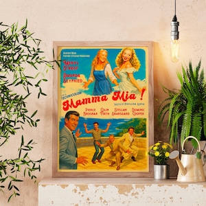 Könnte beinhalten: Ein gerahmtes Vintage-Filmplakat für "Mamma Mia!" zeigt ein farbenfrohes Design mit Schauspielern und dem Filmtitel. Das Plakat wird auf einem Regal mit Pflanzen und einer Gießkanne ausgestellt, wodurch eine dekorative Szene entsteht.