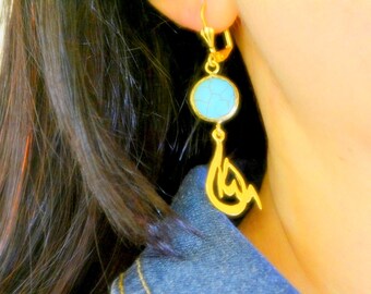 May include: Gold earrings with a turquoise stone and a dangling Arabic calligraphy design.