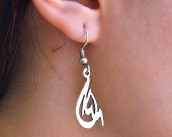 May include: Silver dangle earrings with a delicate, intricate design. The earrings feature a drop-shaped pendant with a stylized Arabic script.