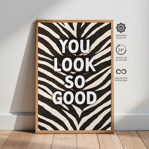 Op de afbeelding: Een ingelijste kunstdruk met een zebraprint achtergrond en de woorden "YOU LOOK SO GOOD" in witte letters. De print zit in een houten lijst. Pictogrammen geven premium kwaliteit, 24-uurs levering en onbeperkte revisies aan.