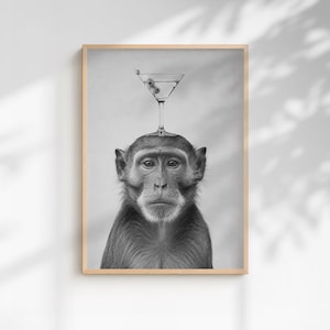 May include: A black and white framed wall art print featuring a monkey with a martini glass balanced on its head. The glass contains liquid and two olives on a toothpick. The monkey is looking directly forward with a neutral facial expression.