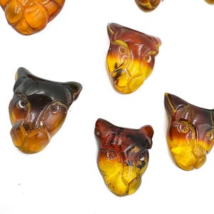 Cabochon a fondo piatto di forma libera, intagliati a forma di gatto, color cognac, in ambra naturale, varie dimensioni.