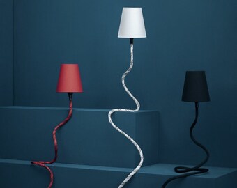 Peut inclure: Trois lampes de table avec des abat-jours et des cordons de couleurs différentes. Les abat-jours sont rouge, blanc et noir. Les cordons sont rouge, blanc et noir. Les lampes sont sur un fond bleu.