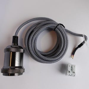 Könnte beinhalten: Ein schwarz-weiß gestreiftes Elektrokabel mit einer Leuchtenfassung in Gunmetal-Grau und einem weißen Klemmenblock. Das Kabel ist aufgerollt und die Fassung hat einen strukturierten Sockel. Die Drähte liegen am Ende des Kabels frei.