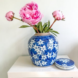 May include: A blue and white porcelain jar with a floral design and a lid. The jar is filled with pink peonies.