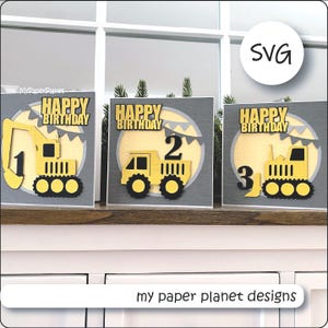 May include: Three birthday cards with yellow construction vehicles, each featuring a different number: 1, 2, and 3. The cards have a gray background with a yellow circle and the words "Happy Birthday". The text "my paper planet designs" is at the bottom.