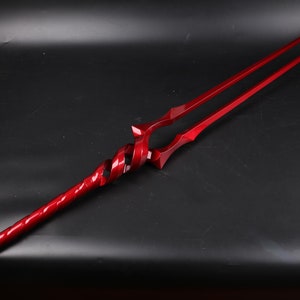 May include: A red metal spear with a twisted handle and a double-pronged tip.