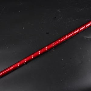 May include: A long, thin, red metal rod with a twisted design. The rod has a pointed tip.