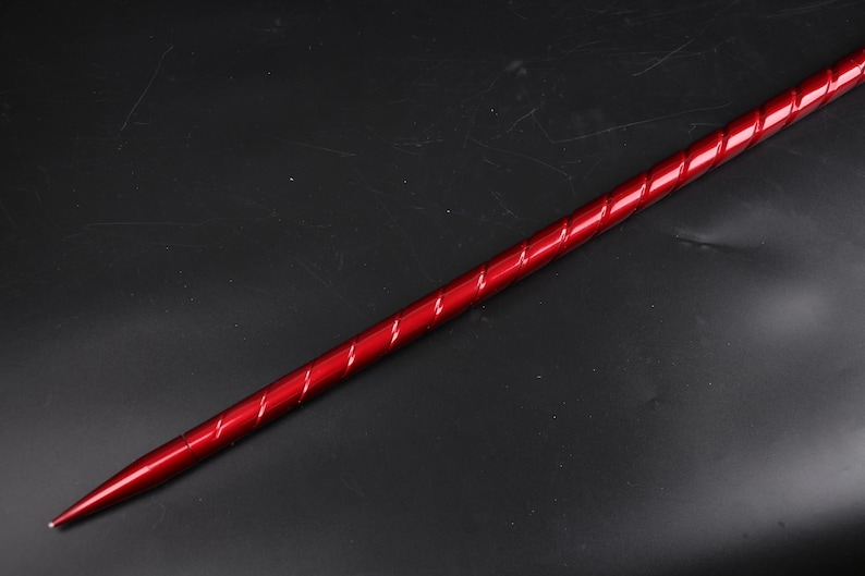 May include: A long, thin, red metal rod with a twisted design. The rod has a pointed tip.