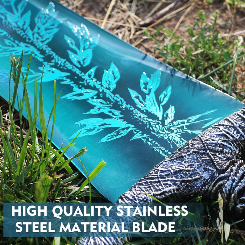 Op de afbeelding: Een close-up van een blauw zwaardblad met een decoratief patroon. De tekst "HIGH QUALITY STAINLESS STEEL MATERIAL BLADE" is zichtbaar onderaan de afbeelding.