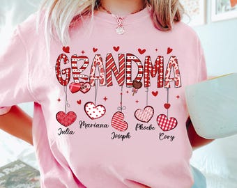 Könnte beinhalten: Pinkes T-Shirt mit dem Wort "Oma" in rot-weißen Streifen, von dem Herzen hängen. Die Herzen tragen die Namen: Julia, Mariana, Joseph, Phoebe und Cory.
