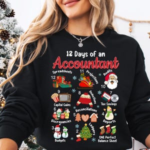 Op de afbeelding: Zwarte sweatshirt met de tekst "12 Days of an Accountant" en kerstafbeeldingen met een boekhoudthema. Bevat illustraties van spreadsheets, audits en andere financiële concepten. Een feestelijk en humoristisch ontwerp.