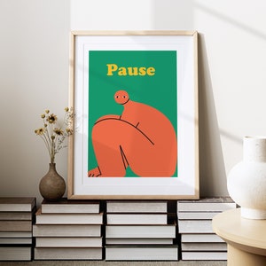 May include: A framed print with a green background and a red figure sitting with the word "Pause" in yellow letters.
