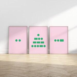 May include: Three framed pink art prints with green geometric designs. The prints are displayed on a wooden floor against a white wall. The designs include dots, rectangles, and circles. The art prints are a modern and minimalist style.