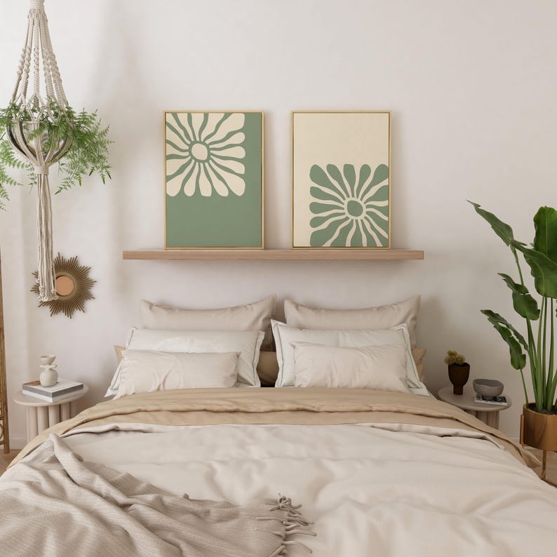 May include: Two framed prints with a green background and a white stylized flower design. The prints are hanging above a bed with beige bedding and pillows.