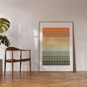 Op de afbeelding: Een ingelijst print met een geometrisch patroon van cirkels in tinten oranje, bruin, beige, groen en blauw. De cirkels zijn in horizontale rijen gerangschikt, waardoor een verloop-effect ontstaat.