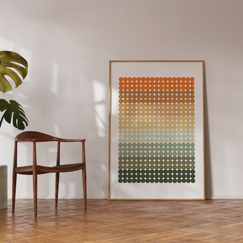 Op de afbeelding: Een ingelijst print met een geometrisch patroon van cirkels in tinten oranje, bruin, beige, groen en blauw. De cirkels zijn in horizontale rijen gerangschikt, waardoor een verloop-effect ontstaat.