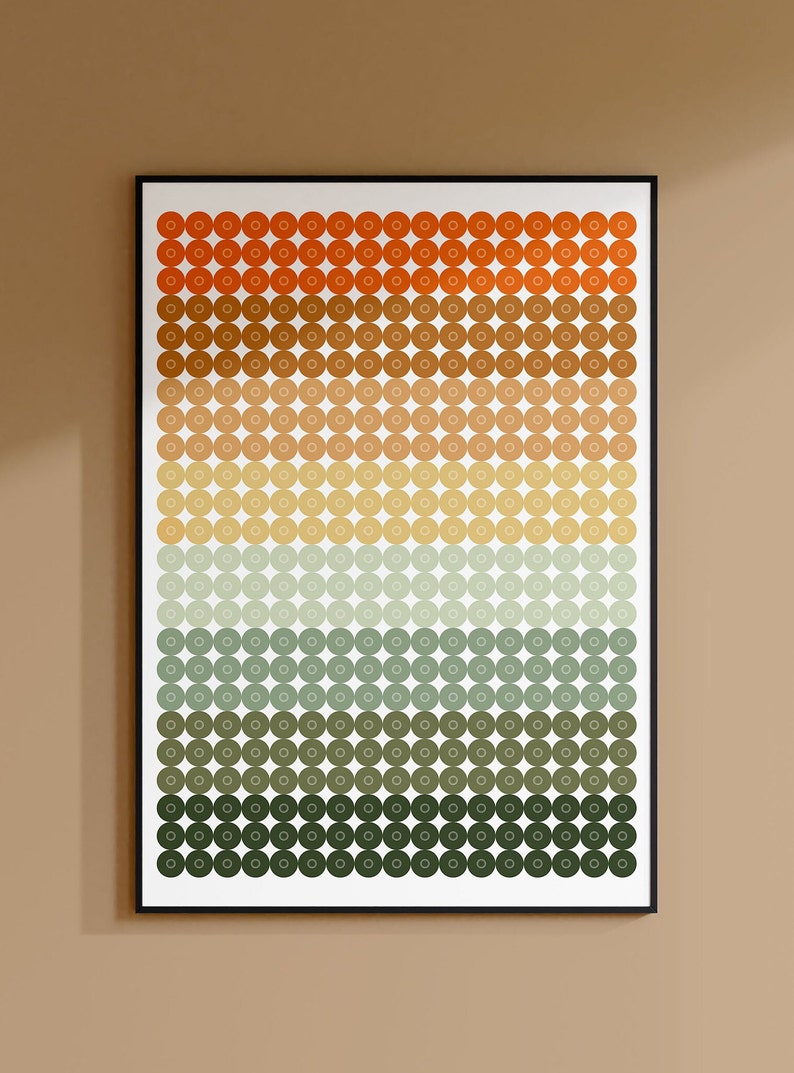 Op de afbeelding: Een ingelijst print met een geometrisch patroon van cirkels in tinten oranje, bruin, geel, groen en grijs. De cirkels zijn gerangschikt in rijen en kolommen, waardoor een verloop-effect ontstaat.