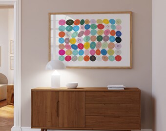 Può includere: Un mobile in legno in stile moderno di metà secolo con due ante e tre cassetti. Una lampada bianca e una piccola ciotola bianca sono appoggiate sopra. Sopra, un'opera d'arte incorniciata con forme circolari colorate. La stanza ha una palette di colori neutri.