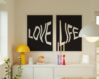 Puede incluir: Dos impresiones enmarcadas en negro con texto blanco en una pared blanca. Las impresiones dicen "LOVE" y "LIFE" en una fuente ondulada. Hay tres candelabros con velas en un estante blanco debajo de las impresiones.