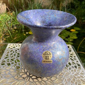Könnte beinhalten: Eine blaue und silberne Keramikvase mit einer weiten Öffnung und einem runden Körper. Die Vase trägt ein Etikett mit der Aufschrift "Ruscha Art echt Handarbeit".