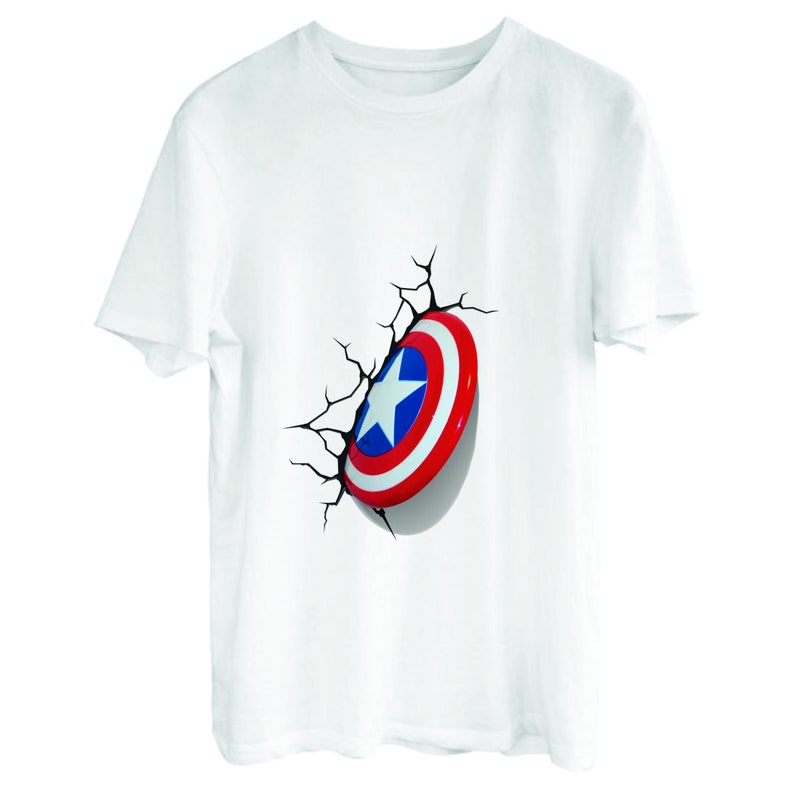 May include: White t-shirt with a red, white, and blue Captain America shield graphic. The shield appears to be breaking through the fabric of the shirt.