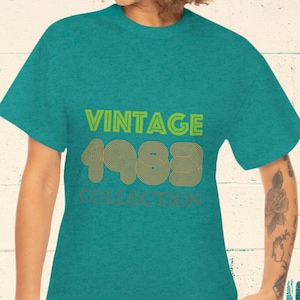 Peut inclure: Un t-shirt bleu turquoise avec le texte "Vintage 1983 Collection" en lettres jaunes et brunes.