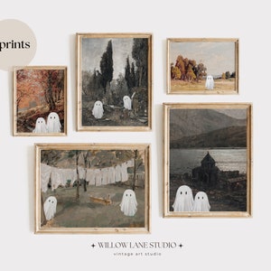 Puede incluir: Cinco impresiones de estilo vintage que representan diferentes paisajes con figuras de fantasmas blancos superpuestas. Las impresiones están enmarcadas en un marco de madera clara y dispuestas en una pared blanca.
