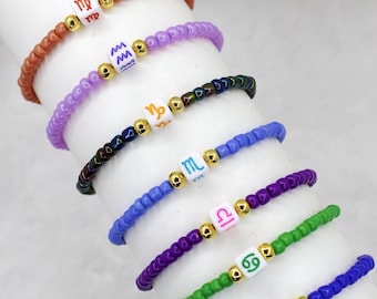 May include: A set of seven colorful beaded bracelets with zodiac signs, including Virgo, Aquarius, Capricorn, Scorpio, Libra, Cancer, and Taurus.