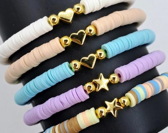 May include: A set of five colorful bracelets with gold heart and star charms. The bracelets are made of small, round beads in shades of white, beige, light blue, lavender, and brown.