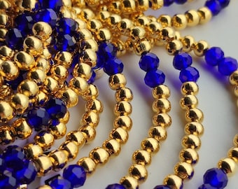 May include: A close-up of a gold and blue beaded bracelet. The bracelet is made of small, round gold beads and larger, faceted blue beads.