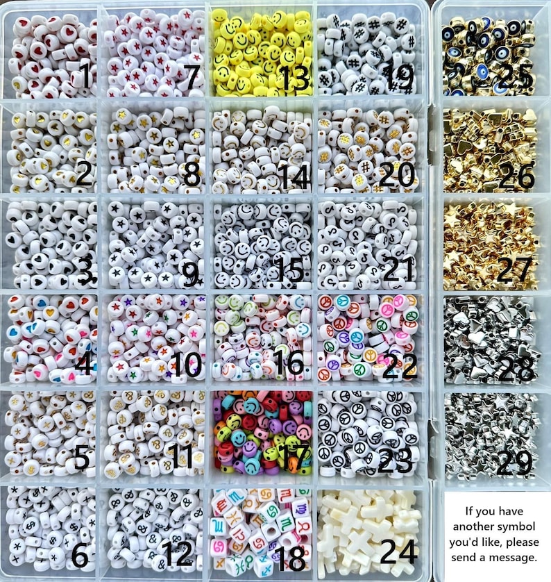 May include: A clear plastic storage container with twenty-nine compartments filled with various small plastic beads. The beads feature symbols including hearts, stars, smiley faces, peace signs, zodiac signs, and letters, labeled with numbers 1 through 29.